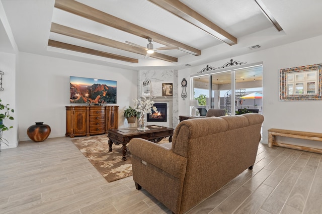 living room with beamed ceiling, ceiling fan, and a premium fireplace