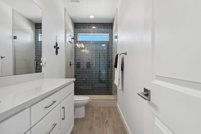 bathroom featuring vanity, a shower with door, and toilet