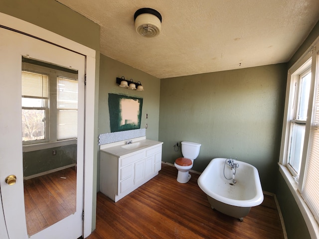 bathroom featuring hardwood / wood-style floors, a bathtub, vanity, toilet, and a textured ceiling