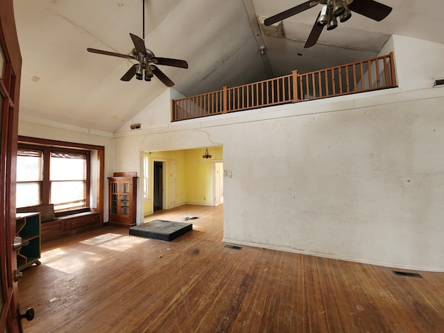 unfurnished living room with hardwood / wood-style floors and high vaulted ceiling