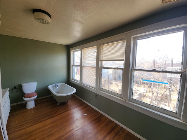 bathroom with toilet, a textured ceiling, vanity, hardwood / wood-style floors, and a washtub