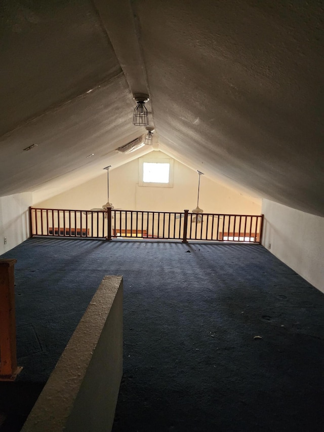 bonus room with vaulted ceiling and dark carpet