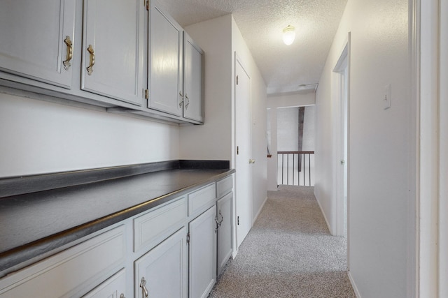 hallway with light carpet and a textured ceiling