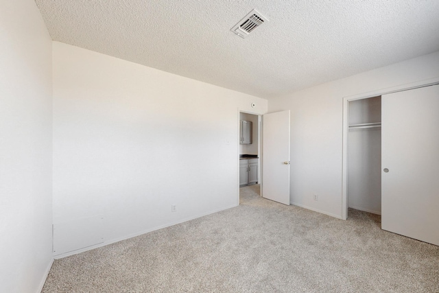 unfurnished bedroom featuring a closet, light carpet, and a textured ceiling