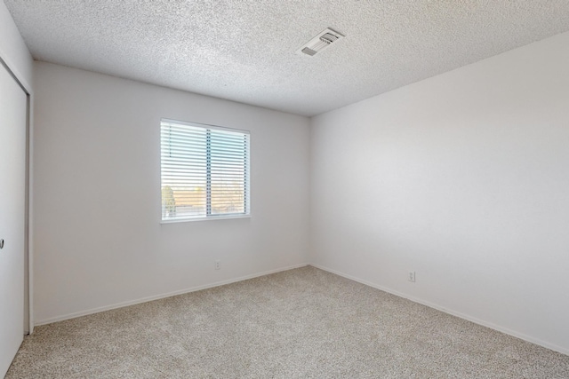 unfurnished room with light colored carpet and a textured ceiling