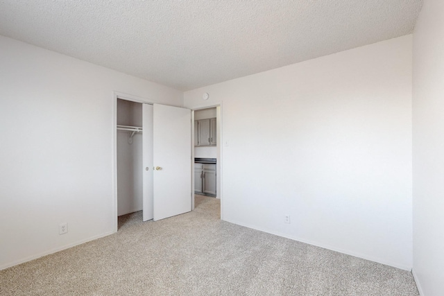 unfurnished bedroom with light carpet, a closet, and a textured ceiling