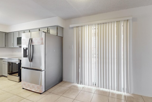 kitchen featuring gray cabinetry, light tile patterned floors, a textured ceiling, and appliances with stainless steel finishes