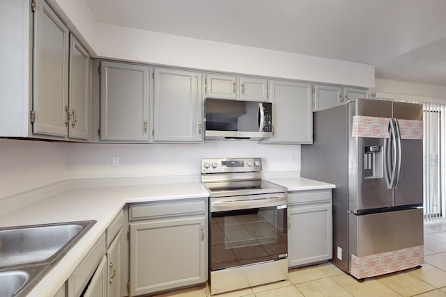 kitchen with light tile patterned flooring, stainless steel appliances, and gray cabinetry