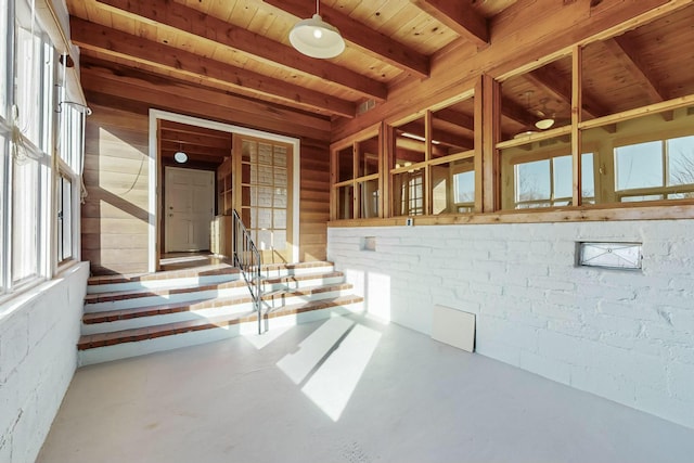 interior space featuring beam ceiling, concrete floors, and wooden ceiling