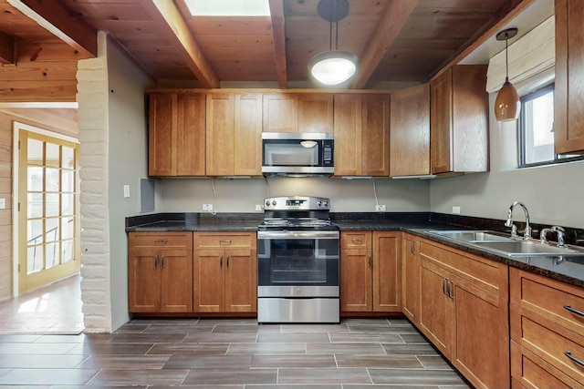 kitchen featuring beamed ceiling, appliances with stainless steel finishes, decorative light fixtures, and sink