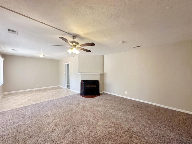 unfurnished living room with a fireplace with flush hearth, light carpet, visible vents, and a textured ceiling