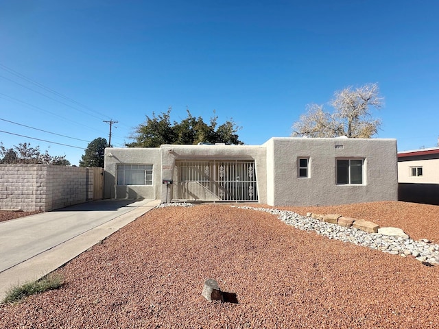 pueblo-style home with fence and stucco siding