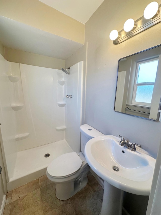 bathroom with toilet, a stall shower, and a sink