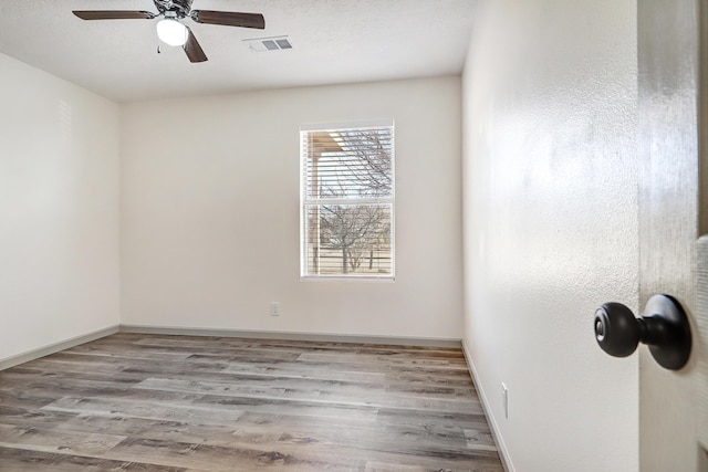 unfurnished room featuring visible vents, light wood-style floors, a ceiling fan, a textured ceiling, and baseboards