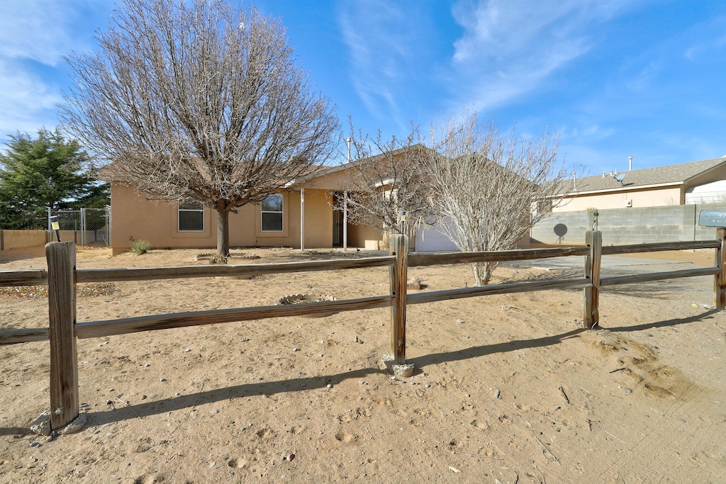 view of front of home with a garage, fence, and stucco siding