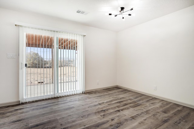 spare room featuring baseboards, visible vents, and dark wood finished floors