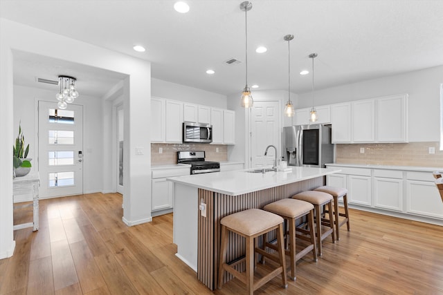 kitchen featuring appliances with stainless steel finishes, sink, a center island with sink, and white cabinets