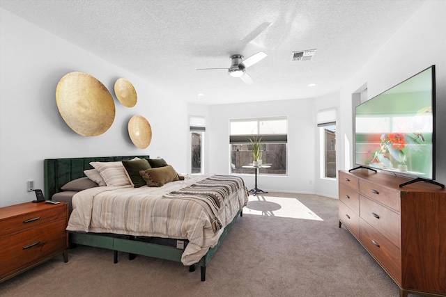 carpeted bedroom with ceiling fan and a textured ceiling