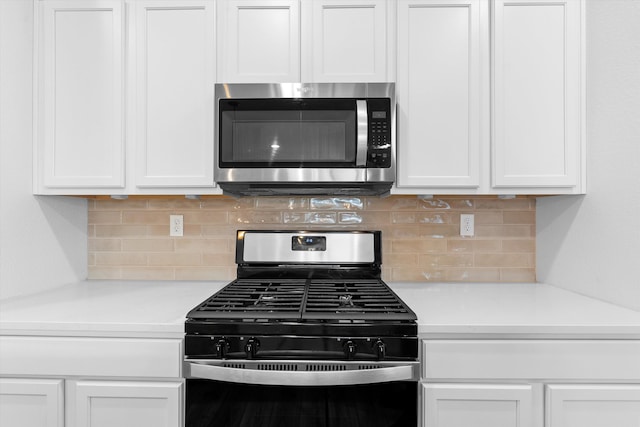 kitchen with backsplash, range with gas stovetop, and white cabinets