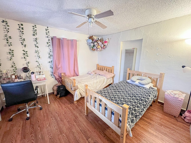 bedroom with ceiling fan, hardwood / wood-style floors, and a textured ceiling