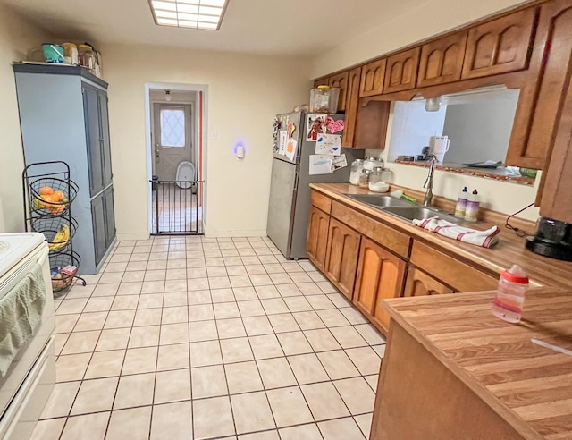 kitchen featuring stainless steel refrigerator, sink, and light tile patterned floors