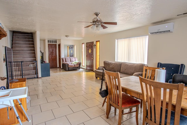 dining space featuring ceiling fan, light tile patterned floors, an AC wall unit, and a textured ceiling