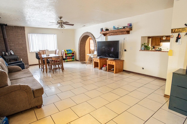 tiled living room with ceiling fan, a wood stove, and a textured ceiling