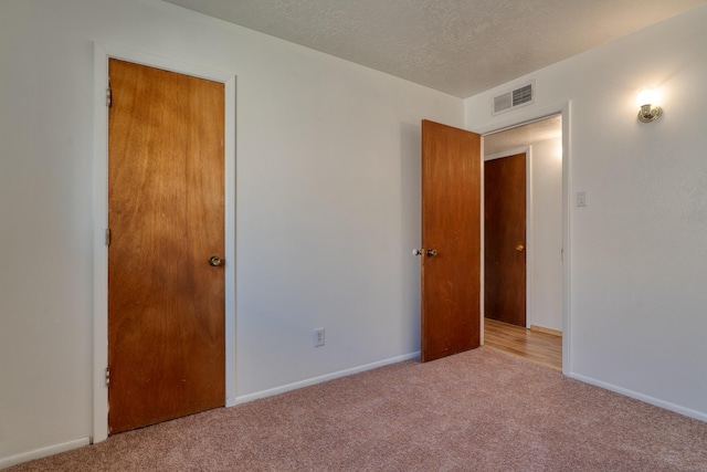 spare room featuring light carpet and a textured ceiling