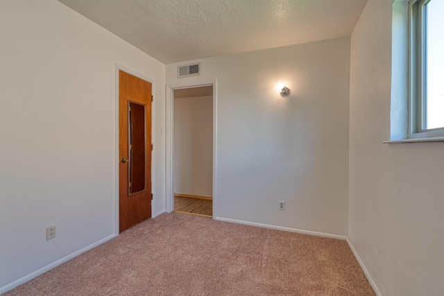 carpeted empty room with a textured ceiling