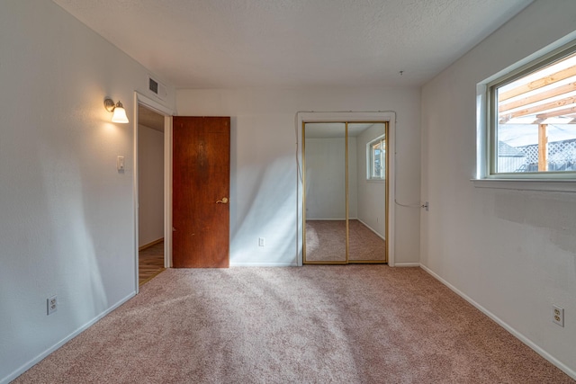 unfurnished bedroom with carpet flooring, a textured ceiling, and a closet