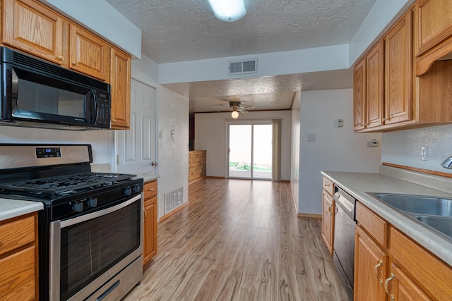 kitchen featuring sink, ceiling fan, stainless steel appliances, light hardwood / wood-style floors, and a textured ceiling