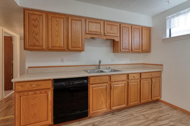 kitchen featuring dishwasher, sink, a textured ceiling, and light wood-type flooring