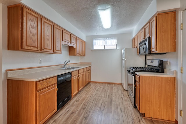 kitchen featuring sink, black appliances, light hardwood / wood-style floors, and a textured ceiling