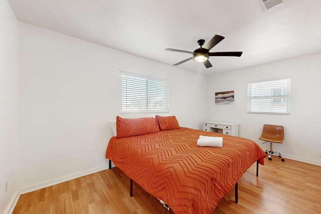 bedroom with hardwood / wood-style flooring, ceiling fan, and multiple windows