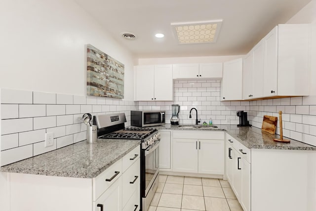 kitchen with sink, white cabinetry, light stone counters, light tile patterned floors, and stainless steel appliances