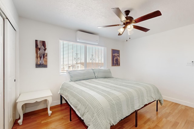 bedroom featuring hardwood / wood-style floors, a wall mounted air conditioner, a textured ceiling, and a closet