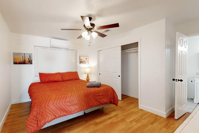 bedroom with ceiling fan, a wall mounted AC, light hardwood / wood-style floors, and a closet