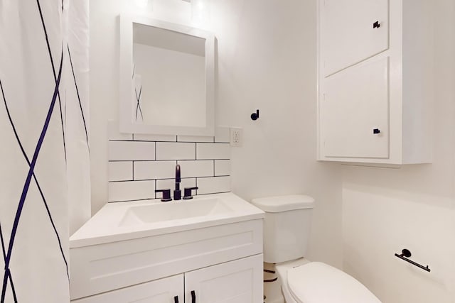 bathroom featuring vanity, toilet, and decorative backsplash