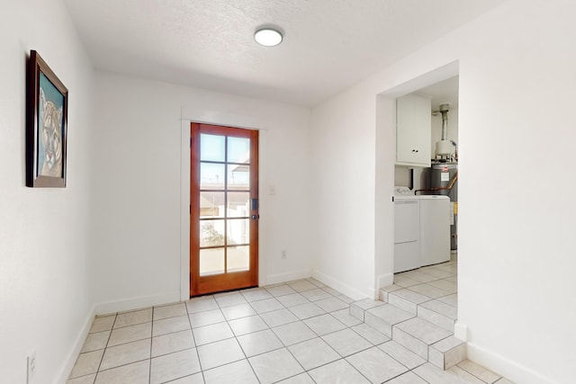 doorway with light tile patterned flooring, washer and dryer, and a textured ceiling