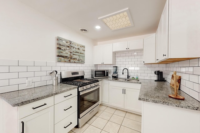 kitchen with sink, white cabinetry, light tile patterned floors, appliances with stainless steel finishes, and light stone countertops