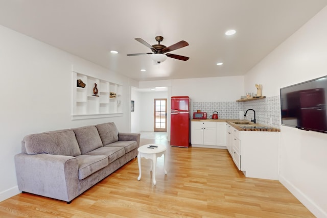 living room with ceiling fan, sink, and light wood-type flooring