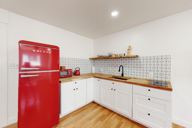 kitchen with white cabinetry, butcher block countertops, sink, and refrigerator