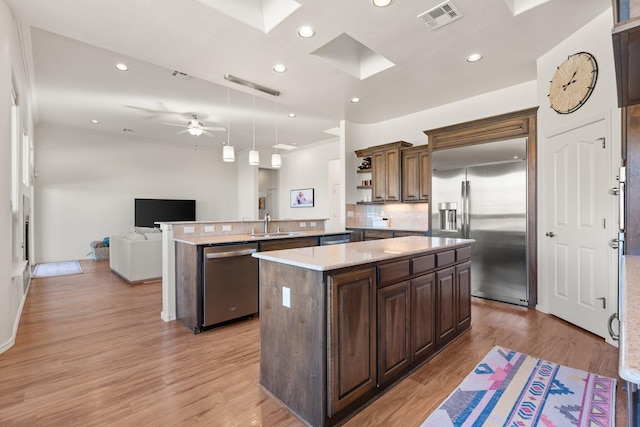 kitchen featuring a kitchen island, appliances with stainless steel finishes, a skylight, hanging light fixtures, and kitchen peninsula