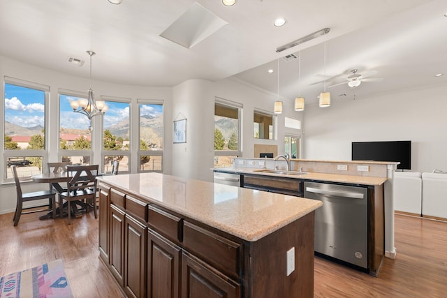 kitchen with pendant lighting, a center island, stainless steel dishwasher, and sink