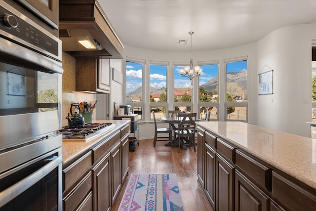 kitchen with pendant lighting, a mountain view, dark brown cabinetry, and appliances with stainless steel finishes