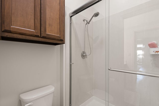 bathroom featuring a shower with shower door and toilet