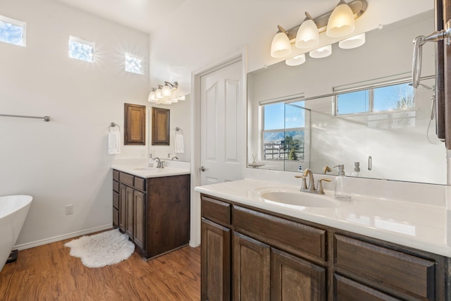 bathroom with a tub to relax in, wood-type flooring, and vanity