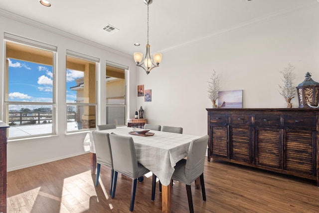 dining space with hardwood / wood-style flooring, ornamental molding, and an inviting chandelier