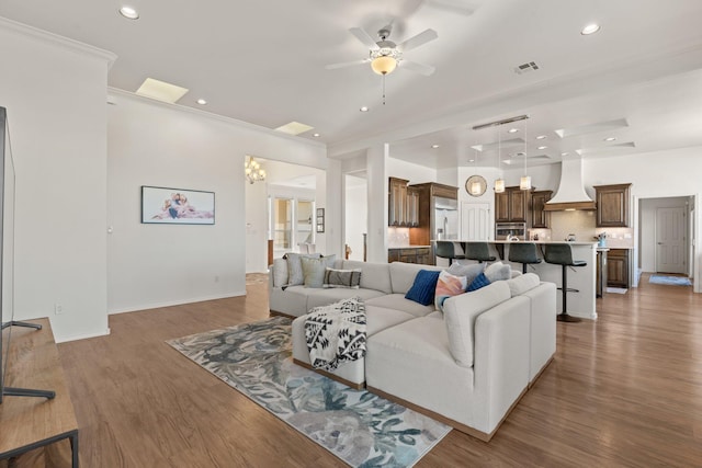 living room with crown molding, ceiling fan with notable chandelier, and dark hardwood / wood-style flooring