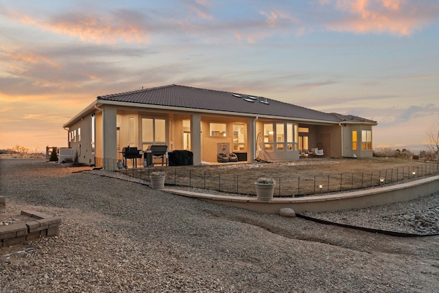 back house at dusk featuring a patio